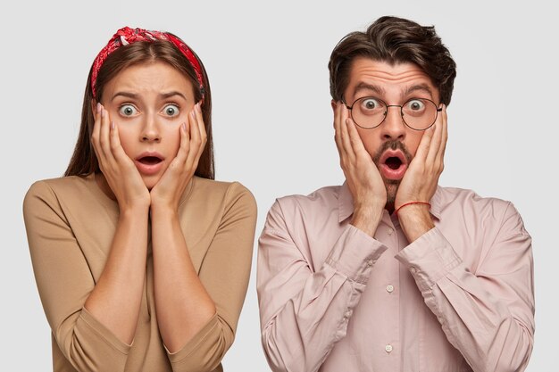 Shocked young couple posing against the white wall