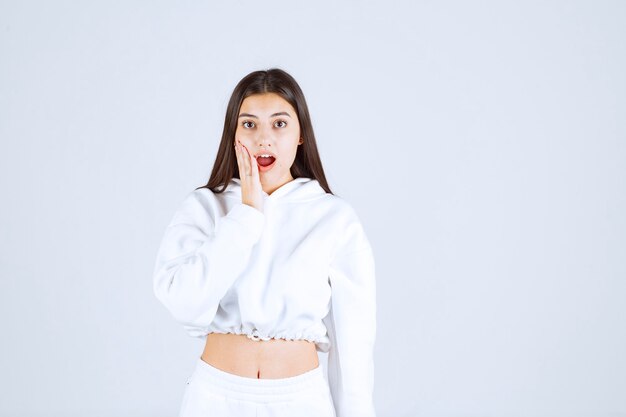 shocked young girl model holding a hand on cheek.