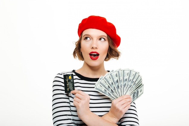 Shocked young lady holding money dollars and credit card