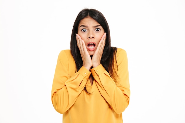 Shocked young lady in yellow shirt standing isolated