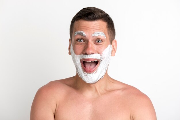 Shocked young man applied shaving cream on beard and eyebrow