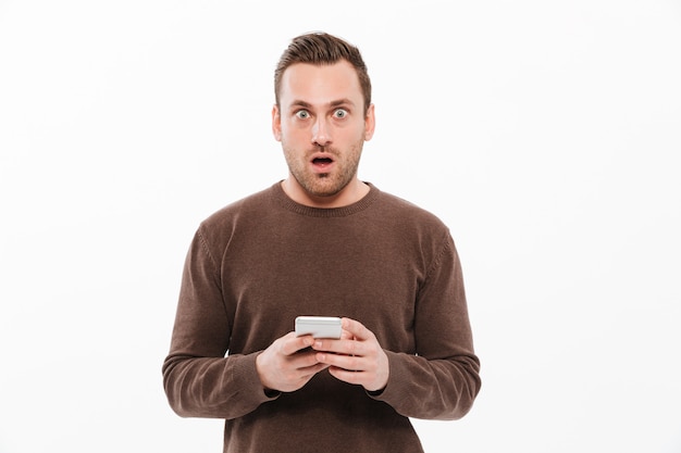 Shocked young man chatting by mobile phone.