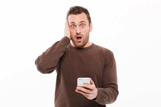 Shocked young man chatting by mobile phone