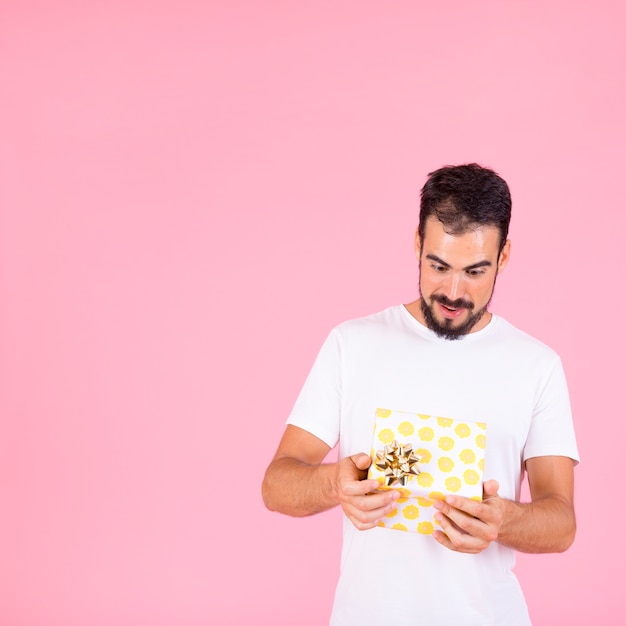 Free photo shocked young man looking at open gift box with golden bow