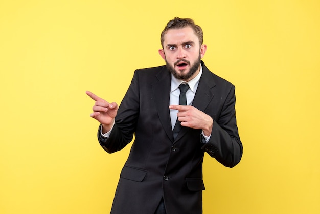 Shocked young man pointing someone on yellow