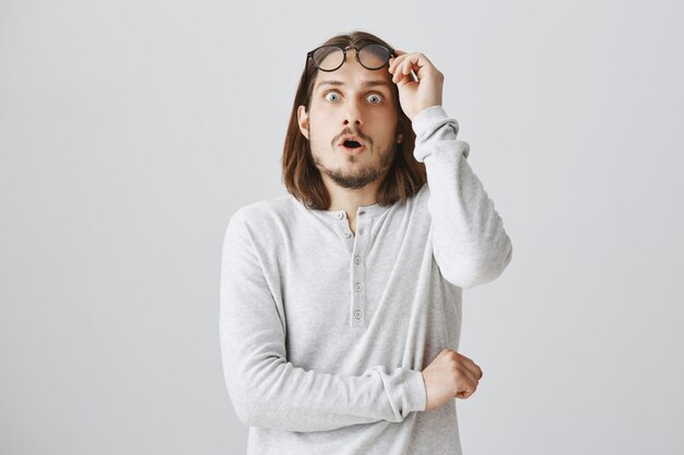 Shocked young man take-off glasses and gasping amazed