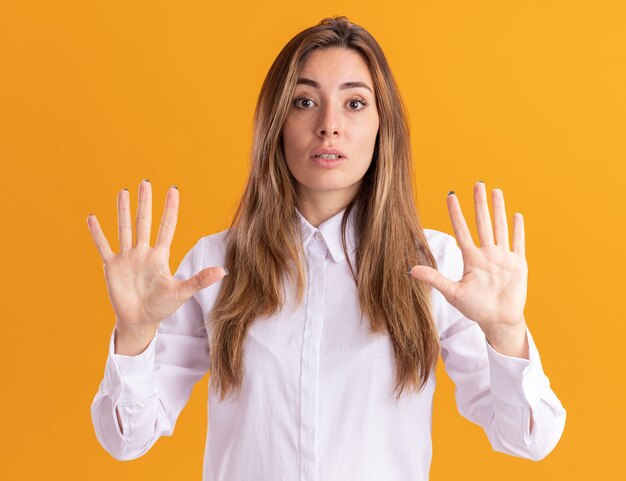 Shocked young pretty caucasian girl stands with raised hands