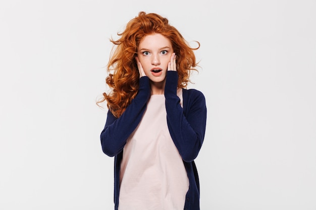 Shocked young redhead lady standing isolated