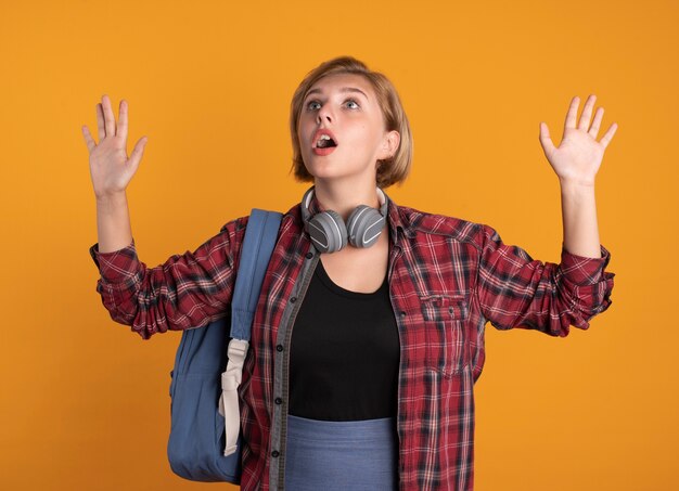 배낭을 착용하는 헤드폰으로 충격을받은 젊은 슬라브 학생 소녀는 제기 손으로 스탠드