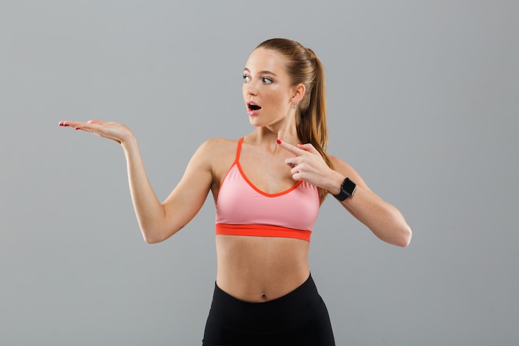Free Photo shocked young sports woman pointing to copyspace.