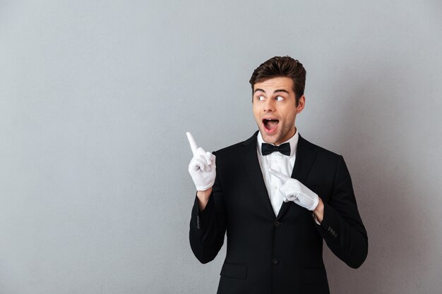 Shocked young waiter pointing.