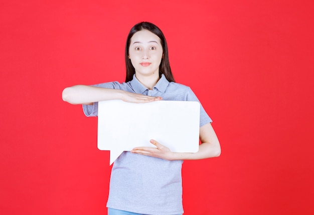 Shocked young woman holding board and looking at front