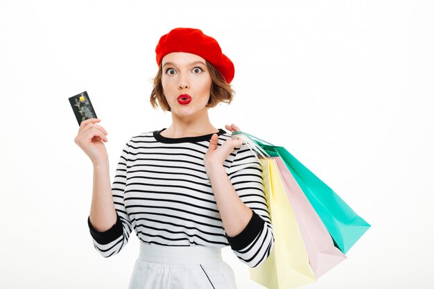 Shocked young woman holding credit card and shopping bags