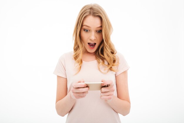 Shocked young woman play games by mobile phone.