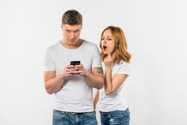 휴대 전화에 그녀의 남자 친구 문자 메시지 근처에 서 충격을 젊은 여자