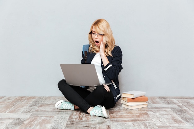 Shocked young woman student using laptop computer.