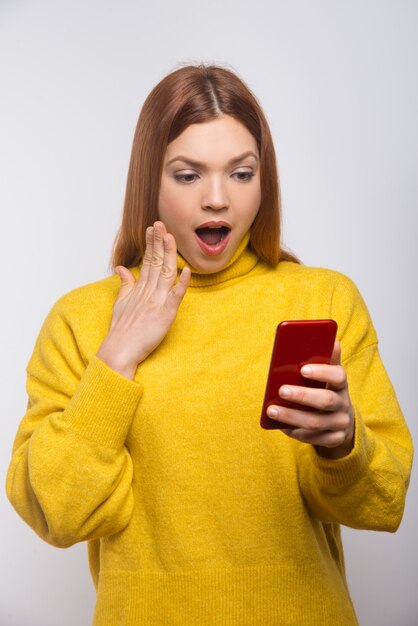 Шокирован молодая женщина, с помощью мобильного телефона