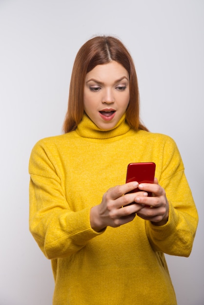 Shocked young woman using smartphone