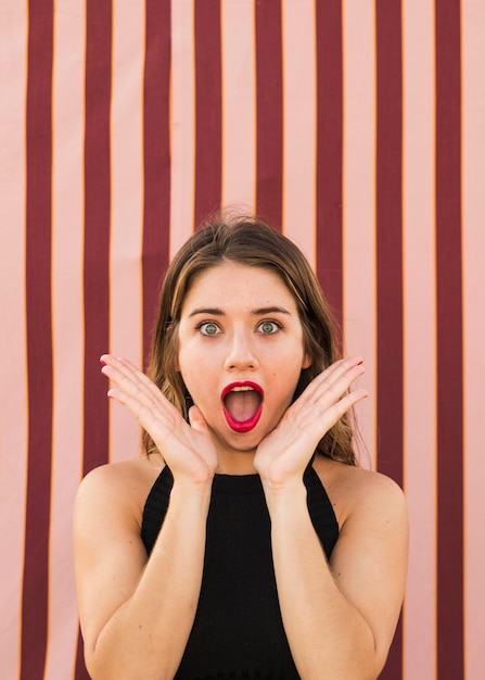 Shocked young woman with her hands under her chin