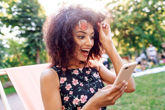 Shocked young woman with open mouth looking on mobile phone