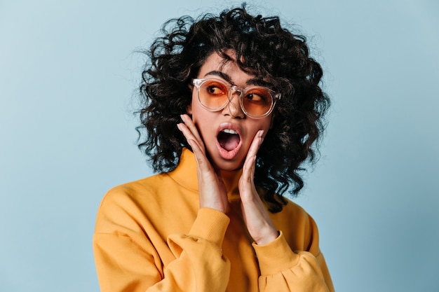 Free photo shocked young woman in yellow sweatshirt looking away