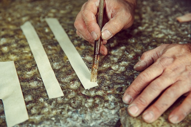 Shoemaker makes shoes for men. He smears special liquid with a brush. The man in female profession. Gender equality concept