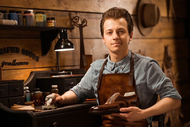 Shoemaker in workshop holding shoes