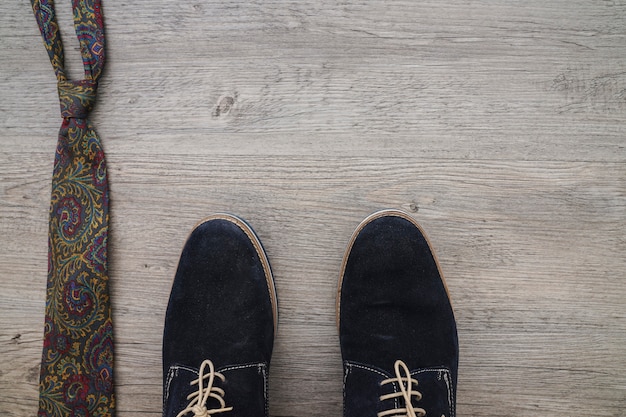 Shoes and necktie on wooden surface