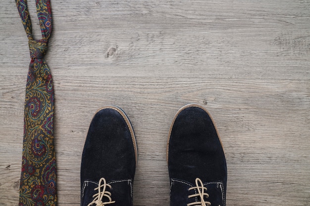 Обувь и галстук на деревянной поверхности