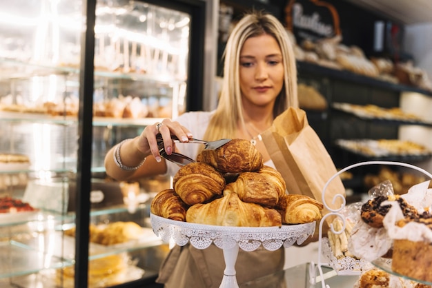 Shop assistant preparing croissant bag