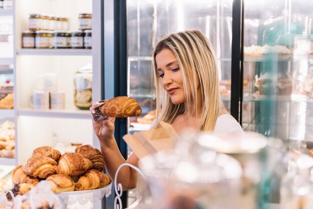 Shop assistant preparing croissant bag