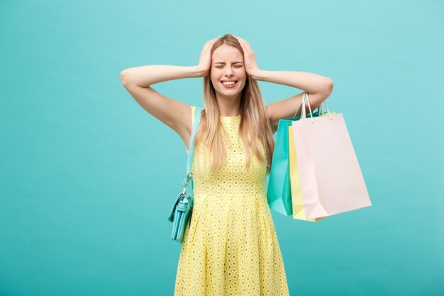 Shoping and Sale Concept: beautiful unhappy young woman in yellow elegant dress with shopping bag.