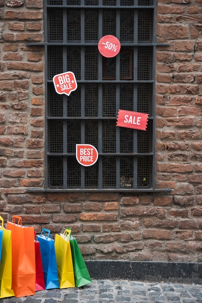 Бесплатное фото Сумки для покупок и продажа таблеток возле окна на кирпичной стене