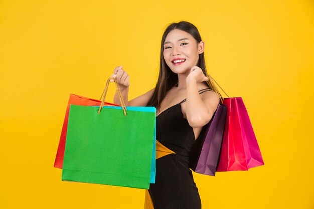 Shopping  beautiful woman holding a colorful paper bag on a yellow  .