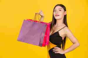 Free photo shopping  beautiful woman holding a colorful paper bag on a yellow  .