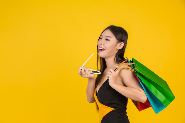 Shopping  beautiful woman holding a colorful paper bag on a yellow  .