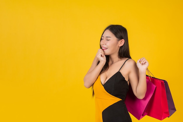 Shopping  beautiful woman holding a colorful paper bag on a yellow  .