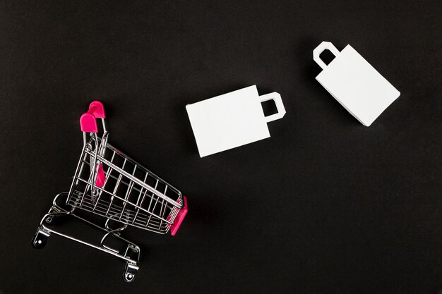 Shopping cart and bags on black background