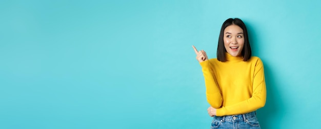 Shopping concept portrait of attractive korean girl in yellow sweater showing promotion offer on cop