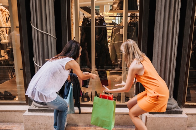 Концепция покупки с женщинами, смотрящими на модный магазин