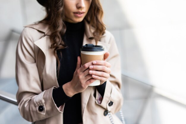 買い物の日。コーヒーブレイク。街の通りを歩いている紙袋を持つ魅力的な若い女性。