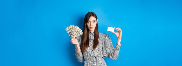 Shopping elegant sassy woman with dollar bills money and plastic credit card looking confident at ca