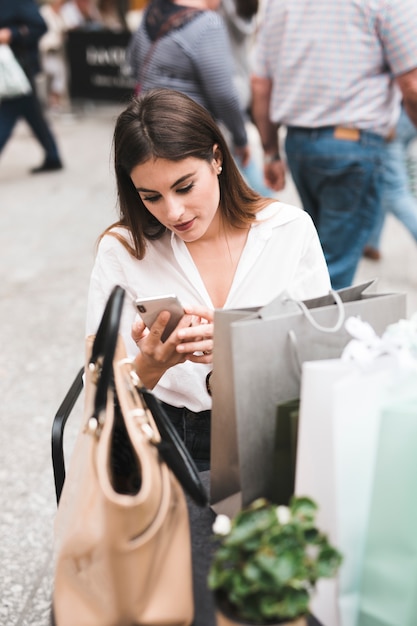 Free photo shopping girl looking at her mobile phone