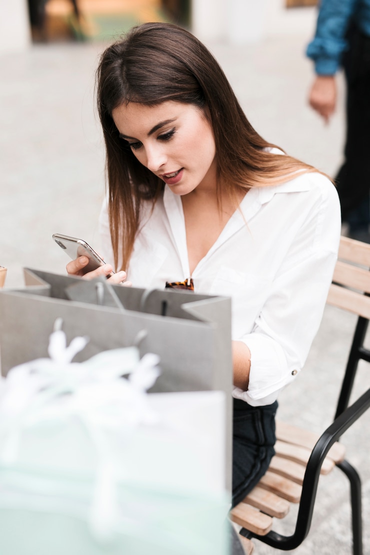 Free Photo shopping girl looking at her mobile phone