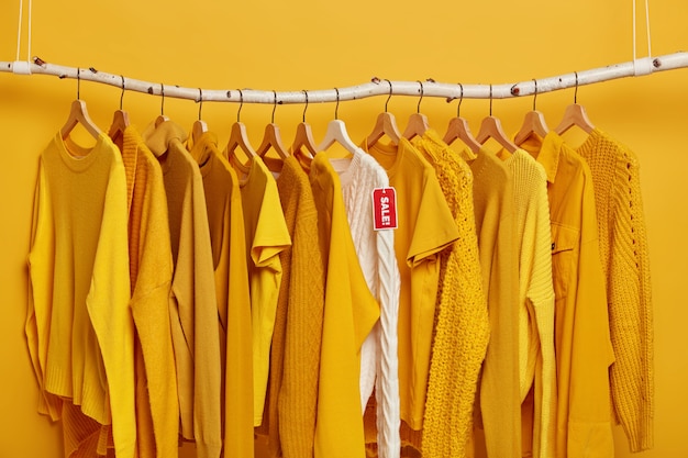쇼핑 및 특별 제공 개념. 많은 노란색 옷 항목과 빨간색 태그 판매와 흰색 니트 스웨터.