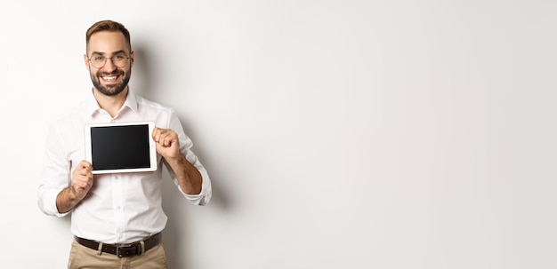 Foto gratuita shopping e tecnologia bell'uomo che mostra lo schermo del tablet digitale con gli occhiali con colletto bianco