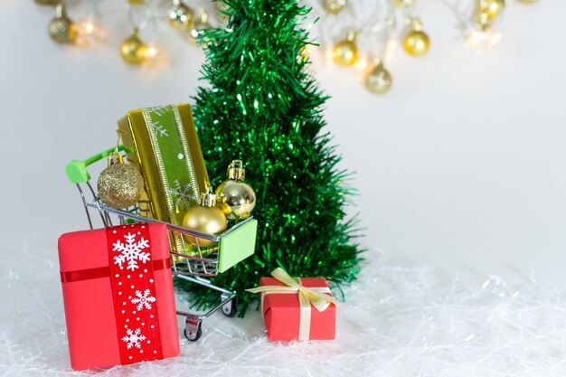 Shopping trolley with gift boxes and golden spheres on snowflakes on a white background