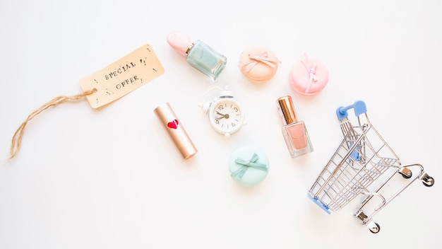 Shopping trolley with little snooze, macaroons, sale tag, lipstick and nail polish