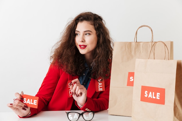 Free photo shopping woman holding sale sign while sitting with shopping bags
