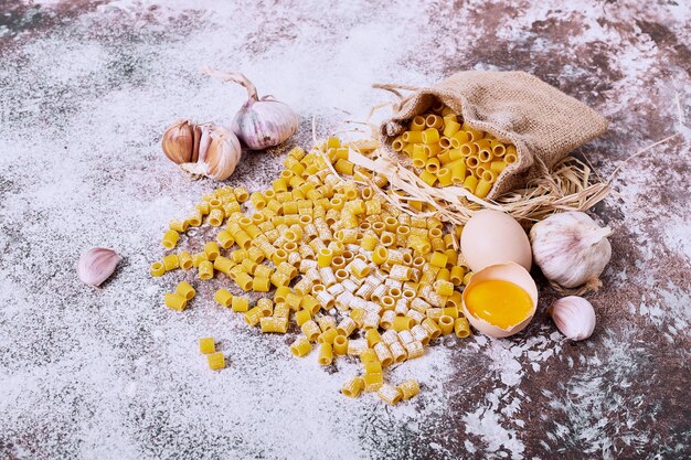 Short cut pasta with garlic and egg yolk on wooden table. 